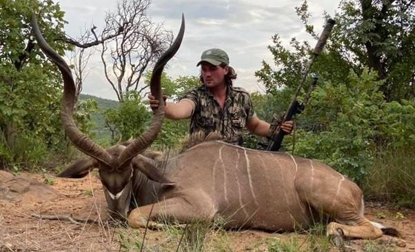 Man holding a rifle, showing his trophy kudu antelope