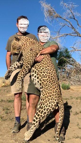 Two men posing with a leopard that they hunted