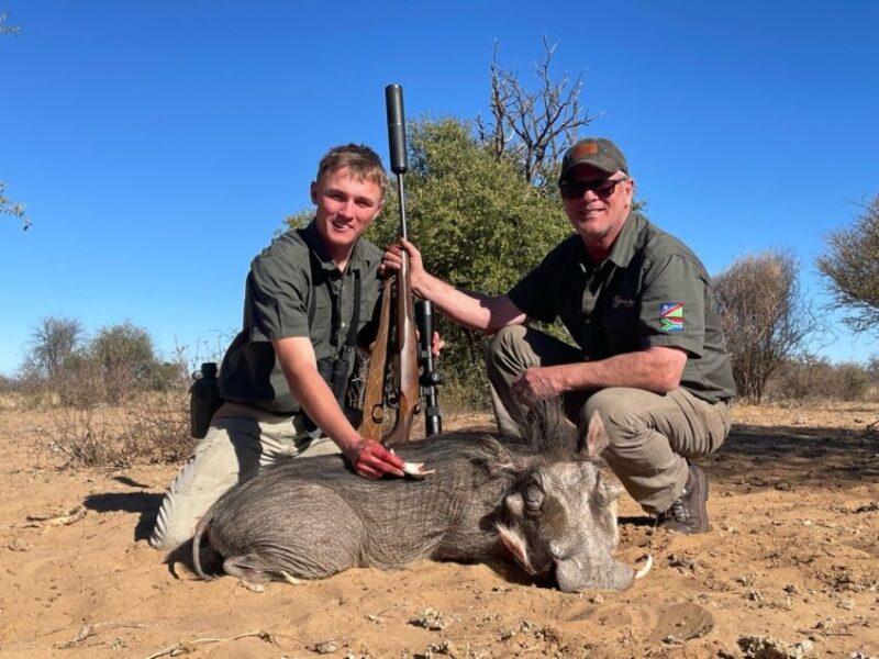 Two men with a trophy warthog they shot.