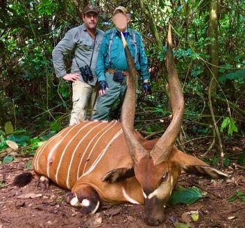 two men standing with a bongo they hunted