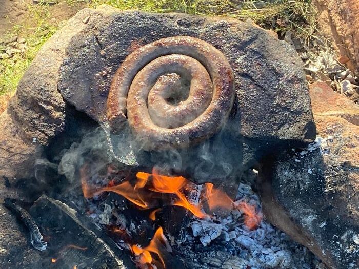 Sausage being cooked over open flames