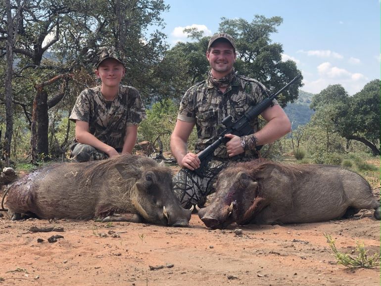 Two hunters posing with their prized warthog trophy