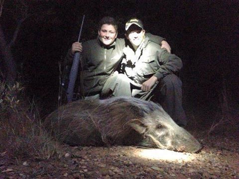 Two boys and their rifles, posing with a bushpig they shot.