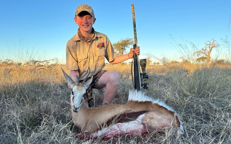 A close up shot of a boy posing with his trophy springbok he shot